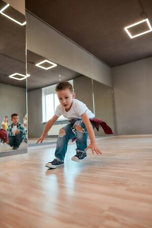 Warming up. Little boys and girls in casual clothes doing sport exercises in the dance studioの写真素材