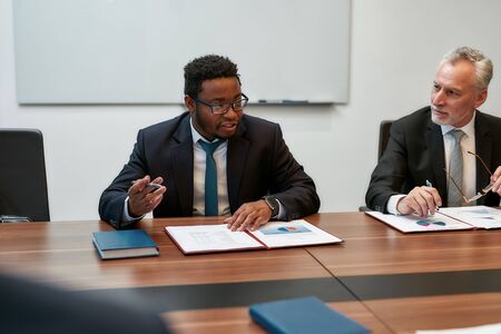 Talking about business. Successful business people in formal wear discussing something while sitting...