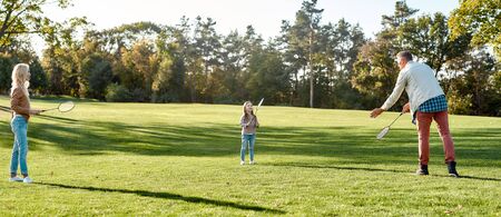 Learning for life. Parents play with daughter in badminton in the park on a sunny dayの写真素材