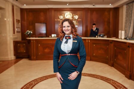 Attractive administrator. Happy female receptionist worker in uniform looking at camera with a smile...