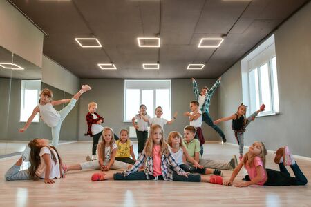 Keep dancing. Group of happy little boys and girls in fashionable clothes posing together in the dance studio. Dance team.の写真素材