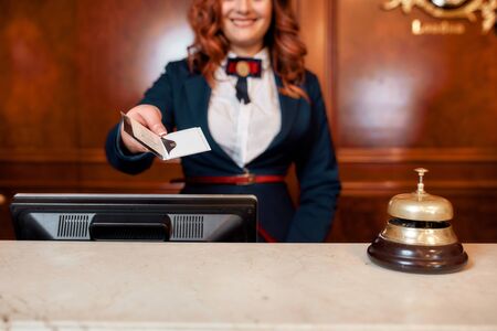 You can use it. Cropped shot of young female executive at the reception desk of a hotel working, giving privileged personal card to a guestの写真素材