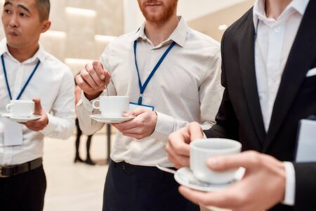 Tea time. Cropped shot of male colleagues having coffee, tea during break at business meeting, forumの写真素材
