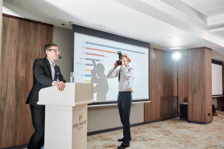 Capture the moment. Full-length shot of photographer taking photo of male speaker giving a talk on corporate business meeting at the conference hallの写真素材