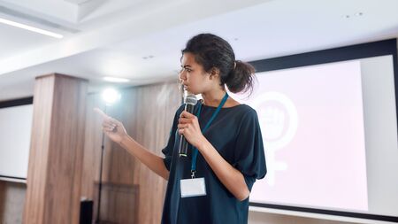 Focus on the Future. Female speaker with microphone giving a powerful talk on corporate business meetingの写真素材