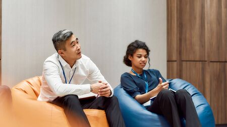 Cozy vibes. Multiethnic work group talking during informal briefing or meeting, discussing business...