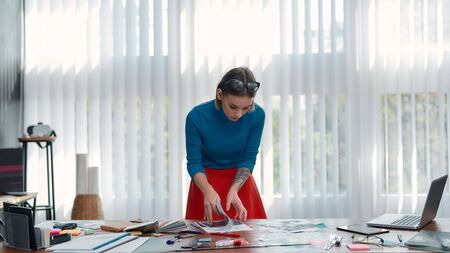 Working on a new project. Young female designer in casual wear analyzing some documents while...