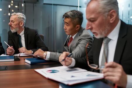 Discussing business. Multicultural business people in formal wear analyzing some documents and...