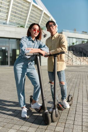Happy weekend. Two friends having fun driving electric scooters on a sunny day