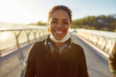 Move on. Positive young african woman wearing medical protective mask smiling at camera and feeling...
