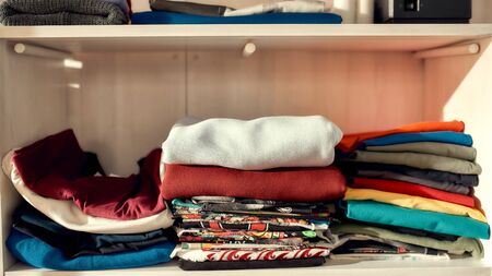 Clothes neatly folded on shelves. Stack of colorful clothing. Horizontal shot. Web Bannerの写真素材