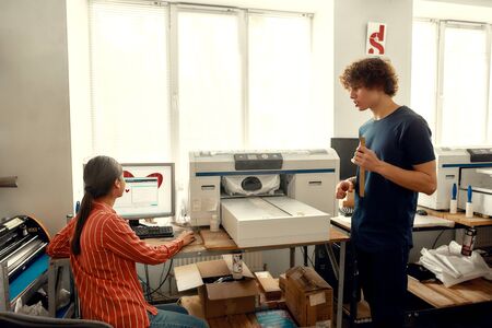 Because we love designing. Young workers, man and woman putting t-shirt for printing in the silk...