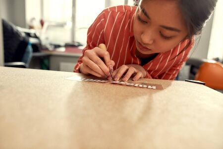 Concentrating on the process. Cropped shot of woman carefully removing the backing from advertisement sticker with text while preparing it to be printed on a T-Shirtの写真素材
