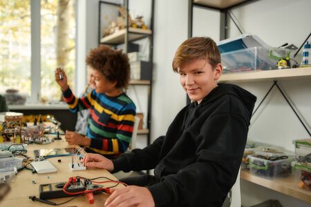 Education is power. Caucasian boy looking at camera while making toys at a technology class. Smart kids and STEM education.の写真素材