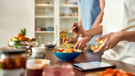 Close up of process of cooking. Couple preparing healthy meal in the kitchen, checking recipe using...