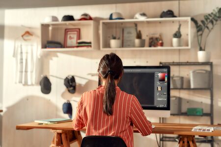 Taking ideas seriously. Portrait of female worker sitting by desk, drawing sketches logo design...