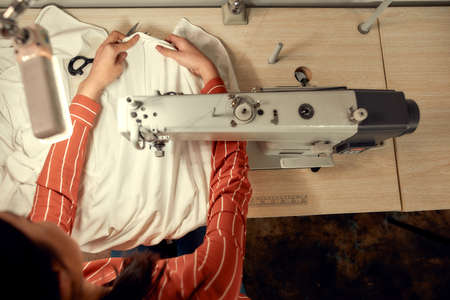 The Joy of Process. Top view of woman seamstress sitting and sewing. Dressmaker working on the...