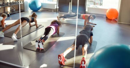 Get in, get fit. Portrait of kids doing plank, exercising together with female trainer in gym. Workout on a sunny day. Sport, healthy life, physical education conceptの写真素材