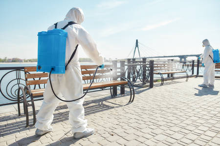 Nobody does it better. Sanitization, cleaning and disinfection of the city due to the emergence of the Covid19 virus. Specialized team in protective suits and masks at work near the riversideの写真素材