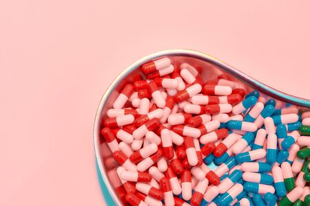 Creative flat lay, top view of different pills, capsules lying in metal box on a pastel pink...