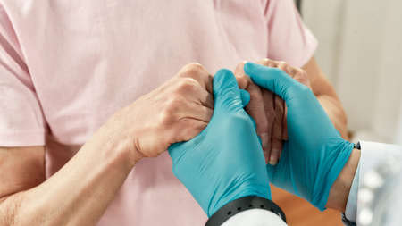 You will be ok. Cropped shot of a doctor in blue sterile gloves holding hands of female senior...