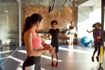 Unstoppable Fitness. Portrait of female trainer controlling, looking after kids, while they are...