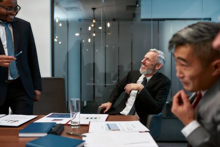 Great results. Portrait of cheerful mature businessman in formal wear listening to his colleague while having a meeting in the modern officeの写真素材