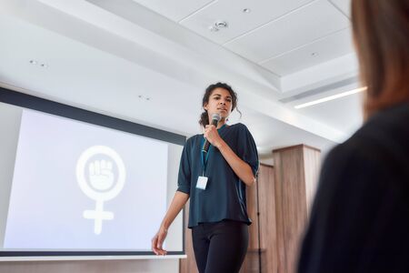 Explore the Possibilities. Female speaker with microphone giving a powerful talk on corporate business meetingの写真素材