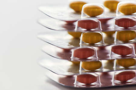 Close up of many pills blister packs lying on each other over white background. Health care,...