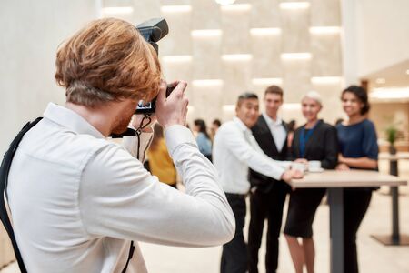 A moment to remember. Close up of photographer taking photo of businesspeople during coffee break at conferenceの写真素材