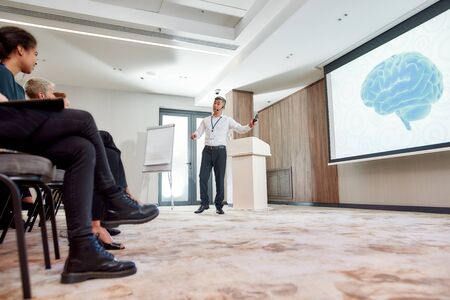 Making a Difference. Full-length shot of asian male speaker in suit with headset and laser pointer...
