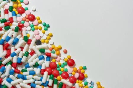 Different pills, capsules scattered diagonally over white background. Health care, vitamins and...