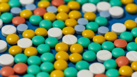 Different colorful pills scattered, lying randomly over blue background. Health care and treatment...