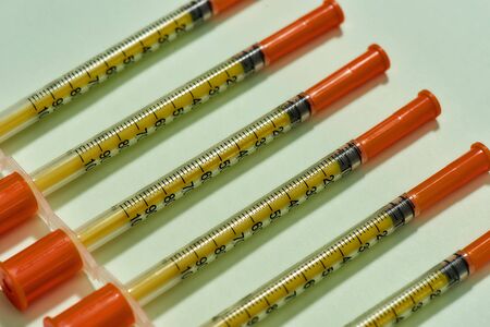 Close up of insulin syringes for diabetes lying diagonally isolated over light background. Injection...
