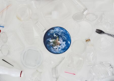 Flatlay composition with different empty plastic containers and conceptual paper model of Earth in the center over white background. The concept of sorting garbage, recycling and eco friendly livingの写真素材