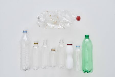 Flatlay composition with different empty plastic bottles lying in orderly manner, in horizontal row over white background. The concept of sorting garbage, recycling and eco living. Horizontal shotの写真素材