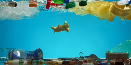 Close up of plastic bags, batteries, food waste and other types of garbage in the blue water. Ecological disaster and pollution of the world ocean conceptの写真素材