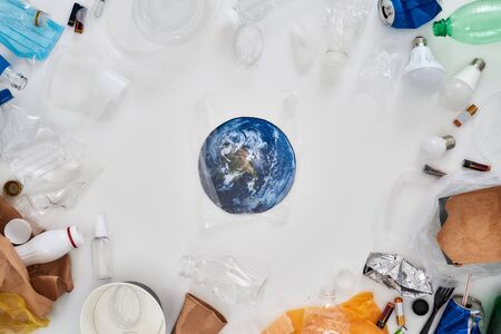 Flatlay composition with different waste, garbage types and paper model of Earth in the center over white background. Sorting, recycling waste concept. Horizontal shot. Top viewの写真素材