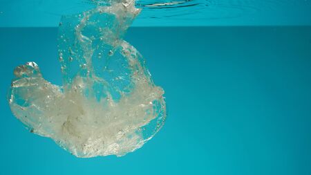 Close up of used polyethylene plastic disposable bag in the blue water. Ecological disaster and...
