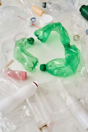 Close up of different used containers and recycle symbol made of green plastic bottles. Recycling...