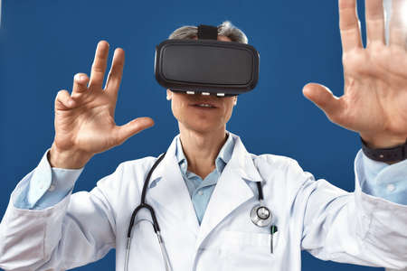 Close up photo of male doctor in medical uniform using virtual reality glasses while standing...