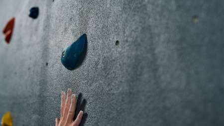 Close up of a hand of woman climbing up on rock wall in gym. Bouldering training concept. Focus on fingers in white dust of magnesia, chalk and boulder. Web Bannerの写真素材