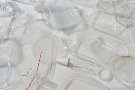 Flatlay composition with used plastic bottles, containers, forks, spoons, egg packaging, caps over...