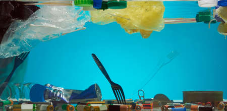 Close up of polyethylene plastic disposable bags and other types of waste in the blue water....
