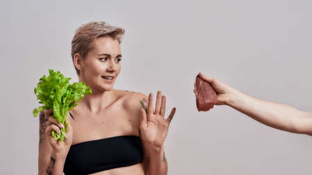 No, thanks. Attractive tattooed woman with pierced nose refuses to eat meat offered to her, choosing...