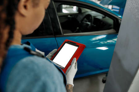 Young african american woman, professional female mechanic looking at the blank screen of tablet pc,...