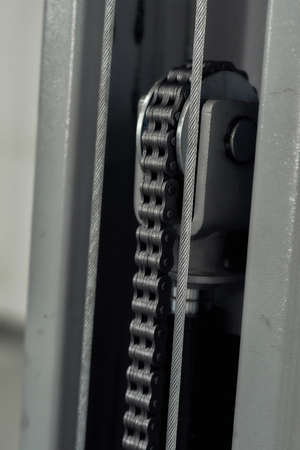 Close up shot elements of fastening steel cables of hoist in car garage. Car service, repair,...