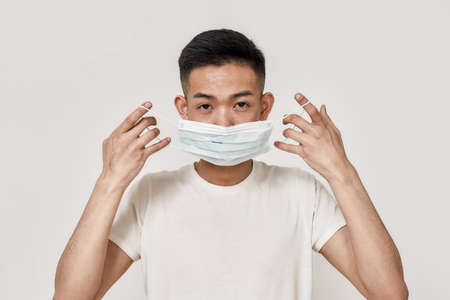 Wear it. Portrait of young asian man wearing medical mask isolated over white background. Health...