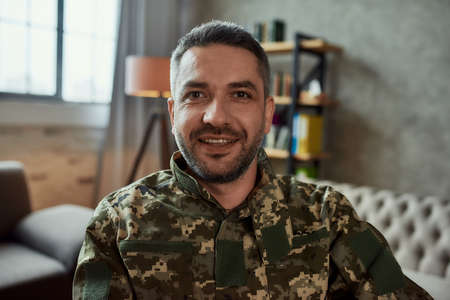 Get better. Portrait of middle aged military man looking at camera with a smile, during therapy session. Disabled soldier suffering from depression, psychological trauma. PTSD conceptの写真素材