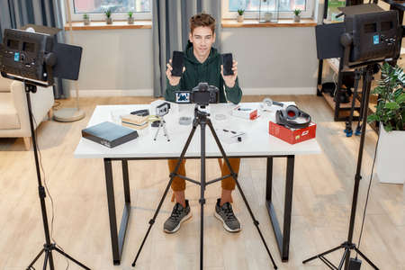 Full length shot of young male technology blogger recording video blog or vlog review of new...